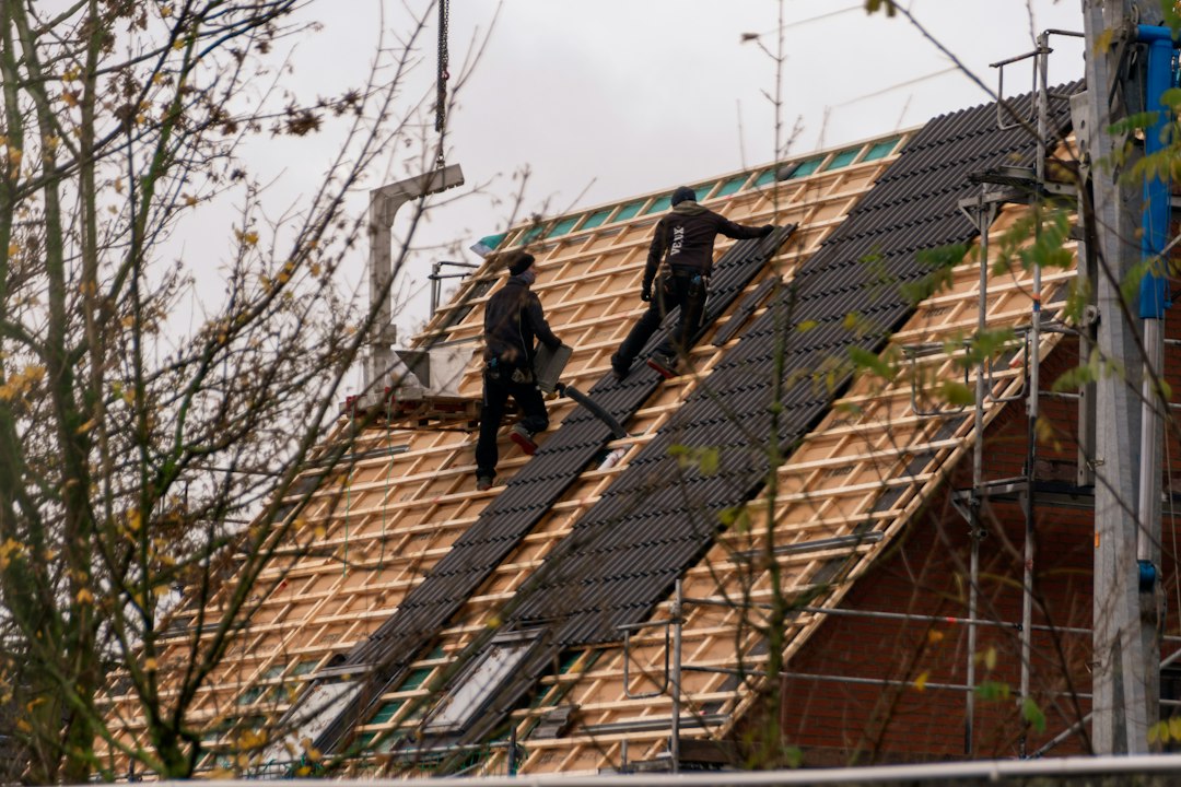 Roofers installing shingles on a steep roof